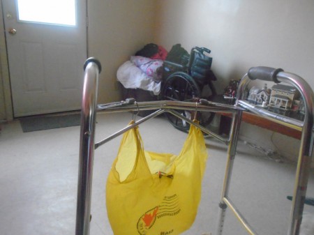 A plastic bag hanging on a walker with shower curtain hooks.