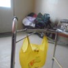 A plastic bag hanging on a walker with shower curtain hooks.