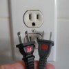Two electrical plugs with red dots on the top side.