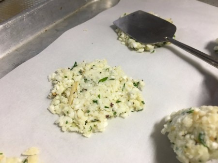 flattening unbaked Cauliflower Cheese Crisps on baking sheet