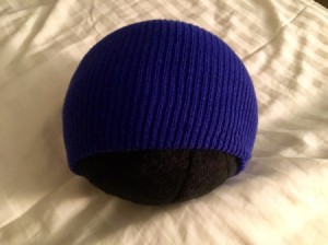 Stretching a tight beanie over a larger stuffed animal.