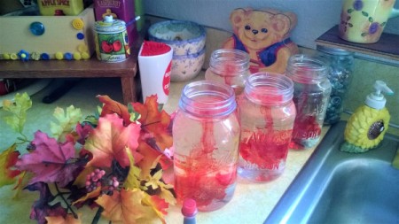 Adding food coloring to glass jars filled with water, for decoration.