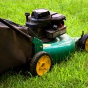 Green lawnmower with yellow wheels on grass.