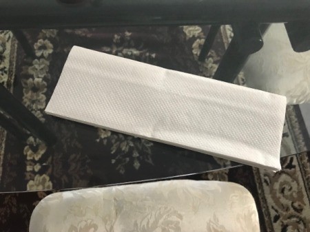A folded white paper towel before being used.