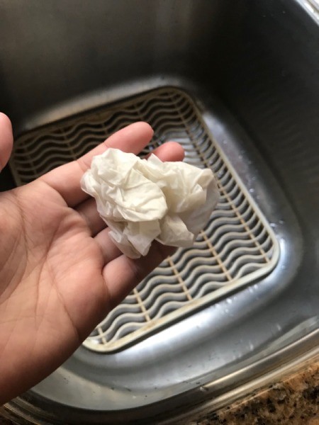 A wadded up paper towel that is wet from hand drying.
