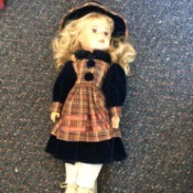 Identifying Porcelain Dolls - blonde doll with plaid apron over dark dress with matching hat