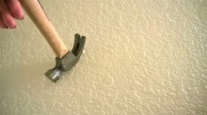 A hammer claw being used upside down to remove a nail from the wall.