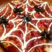 A spooky spider pizza, decorated with spider olives and a ranch web.