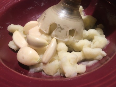 adding garlic to blended potatoes
