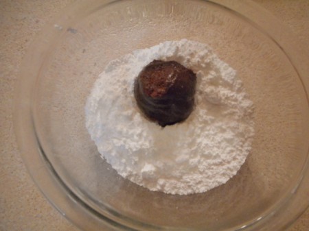 dipping ball of dough in powdered sugar