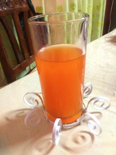 Decorative Recycled Drinking Glass Stand - glass with orange liquid in stand