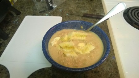 A bowl of cereal with a diced banana on top.