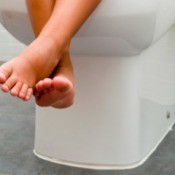 Childs Feet Dangling While Sitting on Toilet