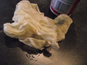 A paper towel used to wipe cooking spray in a pan.