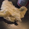 A paper towel used to wipe cooking spray in a pan.