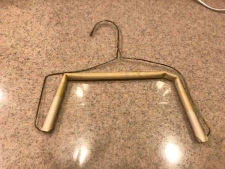 A wire hangar bent to hold smaller sized baby clothes.