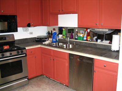 A tiled kitchen counter with red cabinets.