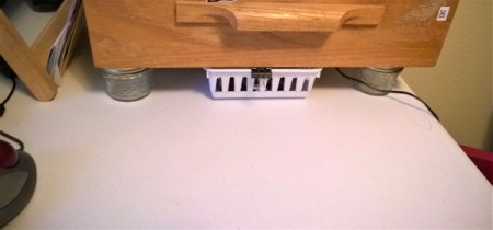 A basket that can slide underneath a storage drawer.