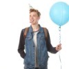 Teenage boy with birthday hat holding a blue balloon.