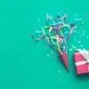 Colorful confetti, streamers and gift box on green color