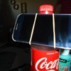 A soda bottle and rubber band being used as a phone stand.