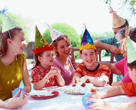 Group of kids with party hats sitting at a table.