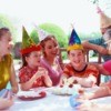Group of kids with party hats sitting at a table.