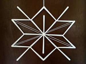 Stick and Yarn Snowflake Decoration - finished snowflake hanging on the wall