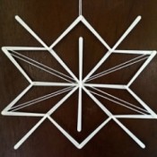 Stick and Yarn Snowflake Decoration - finished snowflake hanging on the wall