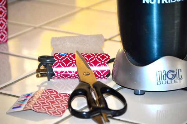 A piece of recycled cardboard from a tissue box, wrapped around an appliance cord.