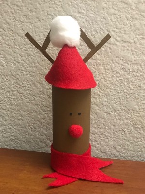 A toilet paper tube decorated like a reindeer and filled with candy.