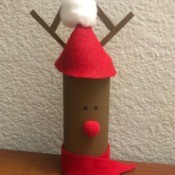 A toilet paper tube decorated like a reindeer and filled with candy.