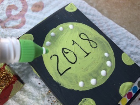 Snack Box New Year's Noisemakers - adding glue dots and sprinkle with glitter