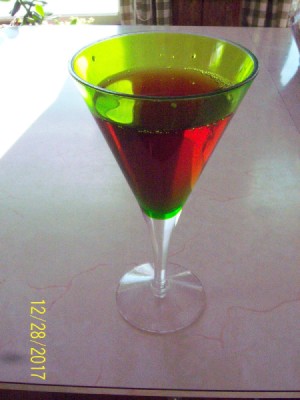 A green glass filled with a red liquid.