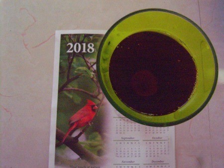 A green glass filled with a red liquid on top of a 2018 calendar.
