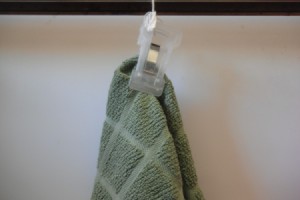 A kitchen towel hung on a oven handle by using a clip.