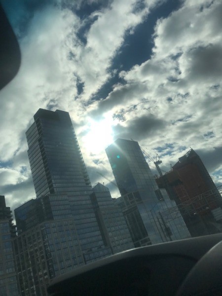 The sun peeking through tall buildings in winter.