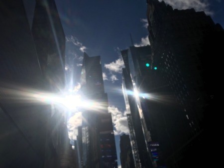 The sun peeking through tall buildings in winter.