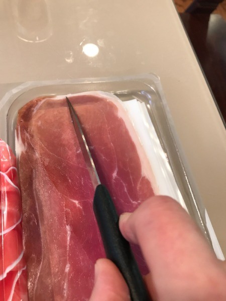 cutting piece of prosciutto in half