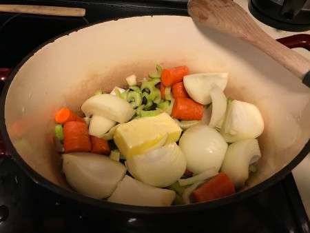 Vegetables being cooked with a cube of butter.