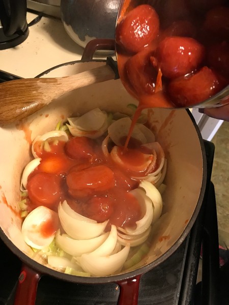 Adding tomatoes to the soup pot.