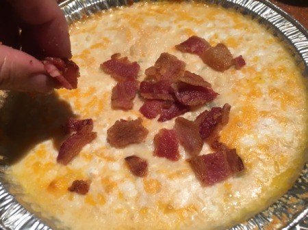 crumbling bacon on cheese