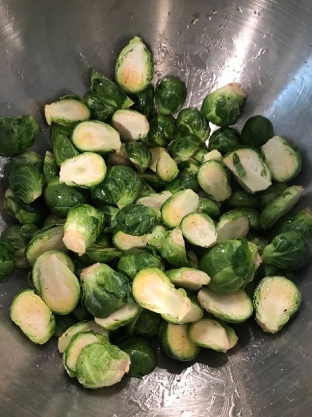 adding olive oil to halved brussels sprouts