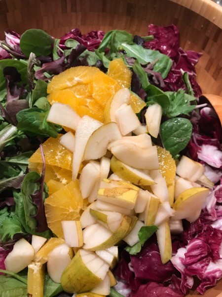 adding pears and oranges to salad