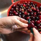 A straw being pushed through a whole cherry, to remove the pit.