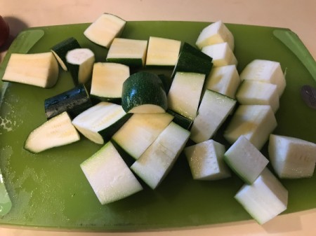 A cutting board full of zucchini that has been cut into sections.