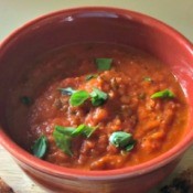 A bowl of Roasted Tomato Soup with basil as a garnish.