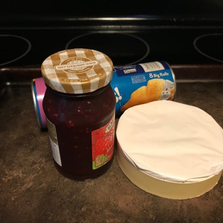 A jar of jam, a package of refrigerator crescent rolls and a package of brie.