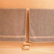 A shower rod in the bathtub used for hanging towels.