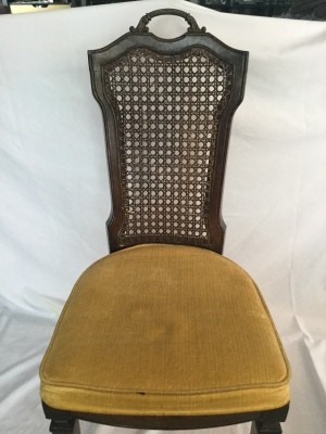 Dark wood chair with upholstered seat and narrow cane back.